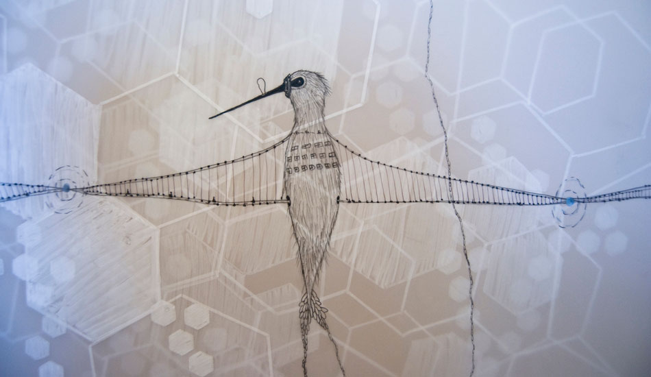 A hummingbird rests on layered Mylar and brown paper.