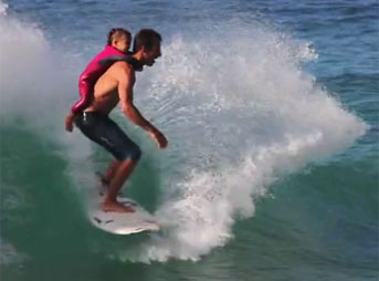 Cory Lopez surfs with his daughter on his back.