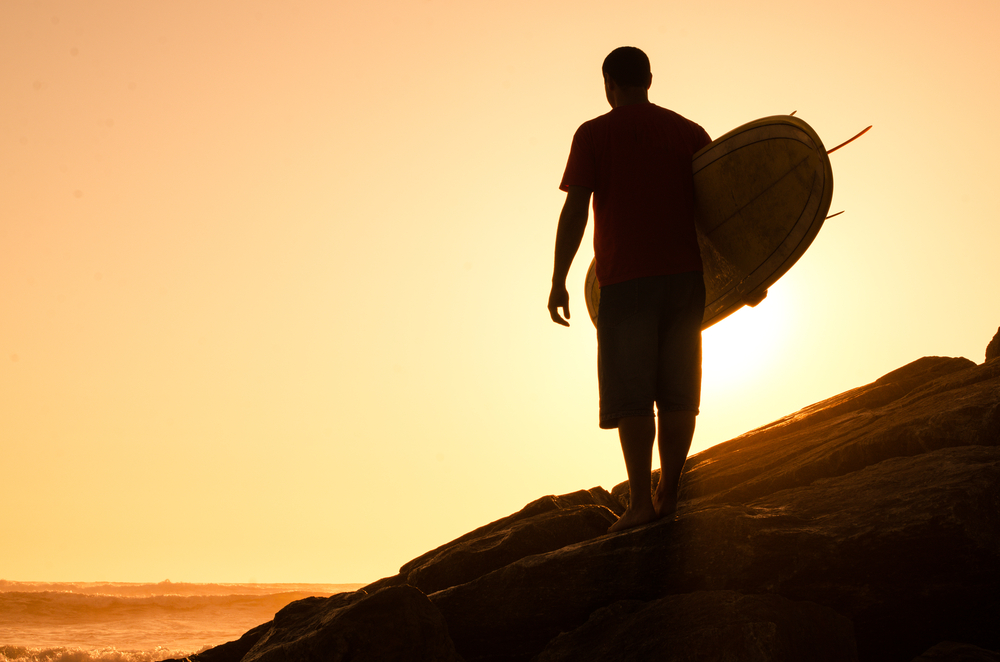 Surfer looks back at sunset.
