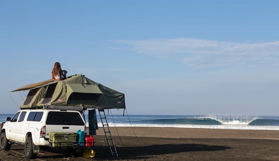 Car and rooftop tent with a breaking wave in Mexico.