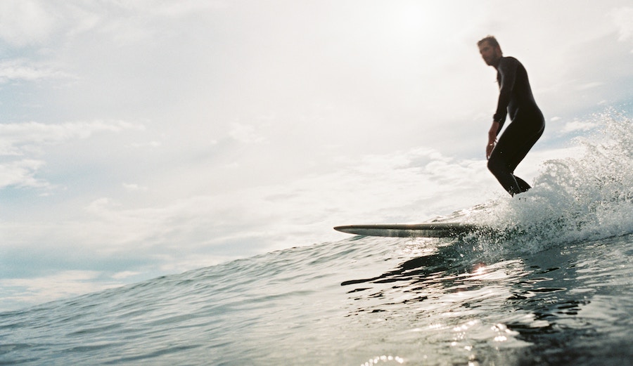 A surfer skims along on a longboard.