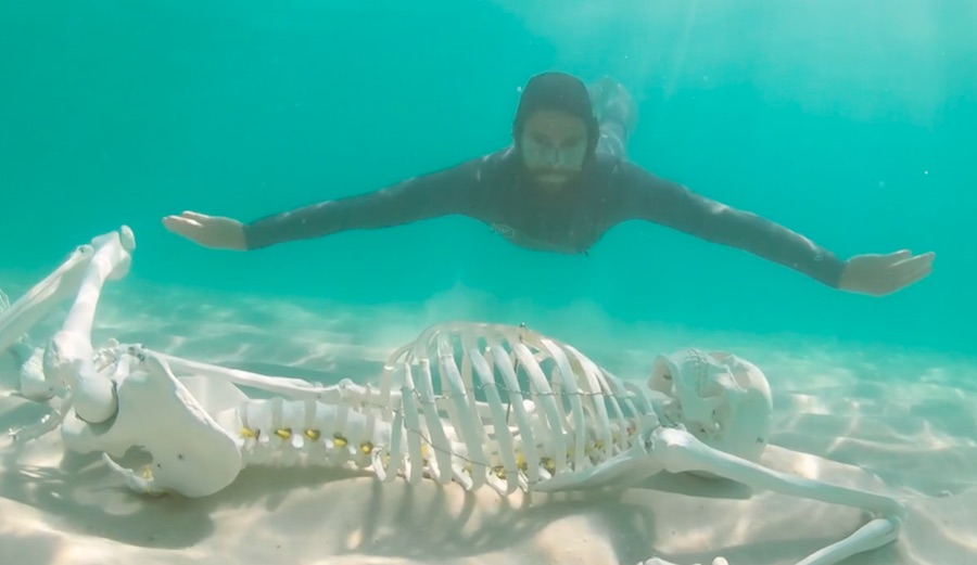 Sterling Spencer swimming underwater with skeleton.