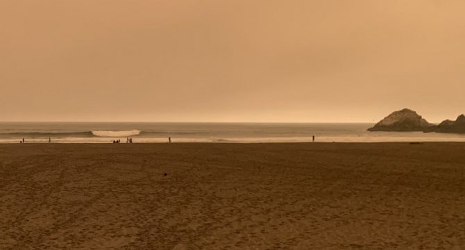 orange smokey skies above ocean beach