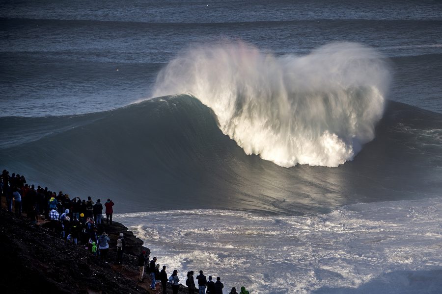 A big wave in Nazare, Portugal with crowds.