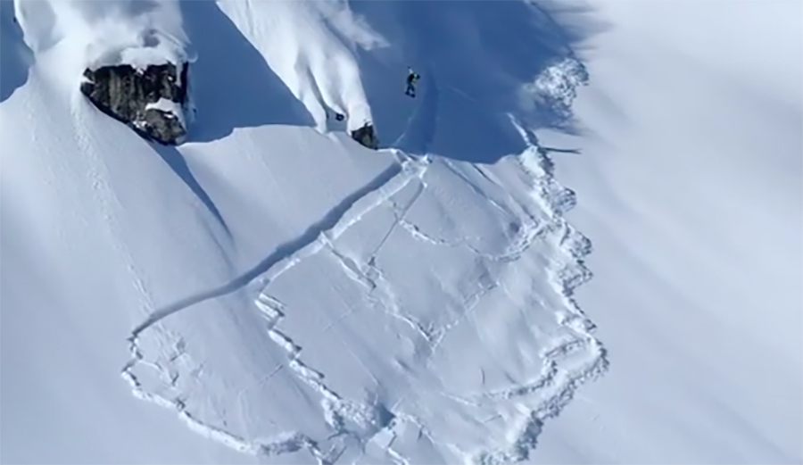 Snowboarder Rusty Ockenden drops big cliff while navigating avalanche