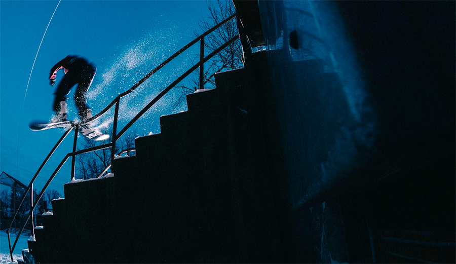 snowboarder riding a rail at night