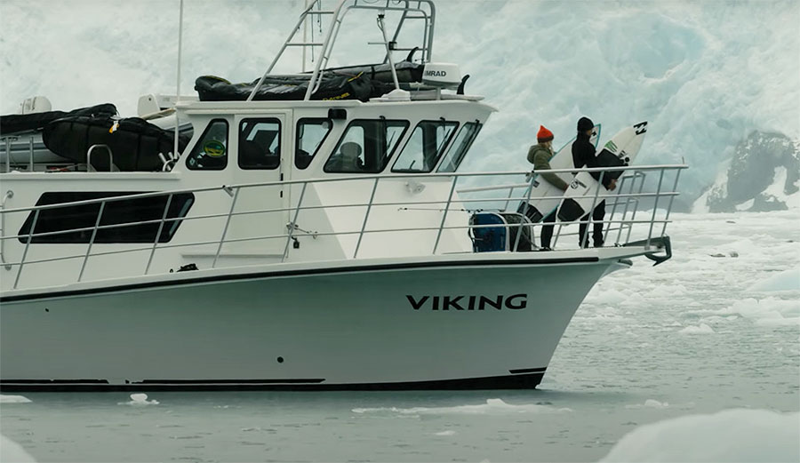 Surfers on boat in Alaska with surfboards