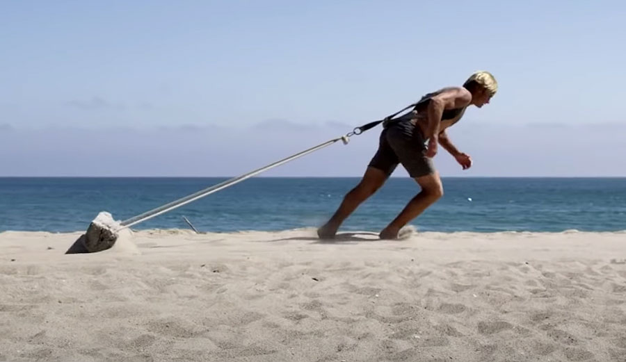 Laird Hamilton draggin a log through the sand