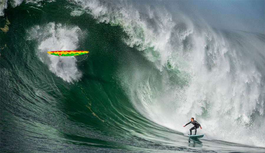 Ian Walsh on a giant wave at Mavericks as a surfboard falls from the lip