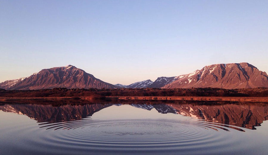 Ripples in pond in front of mountains