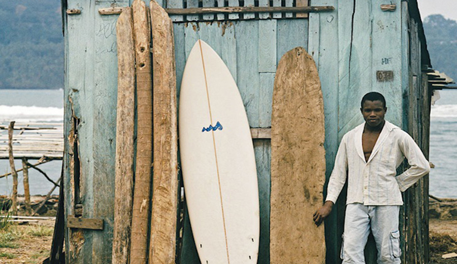 A surfer stands next to traditional boards in africa