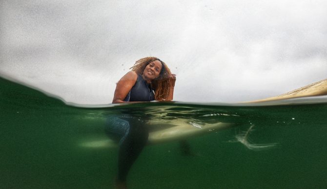 Mimi Miller, organizer of Indigenous Beach Culture Film Festival on a surfboard