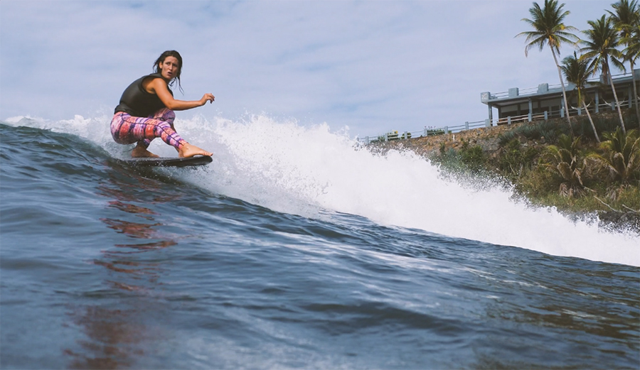 Kassia Meador riding a wave on a longboard