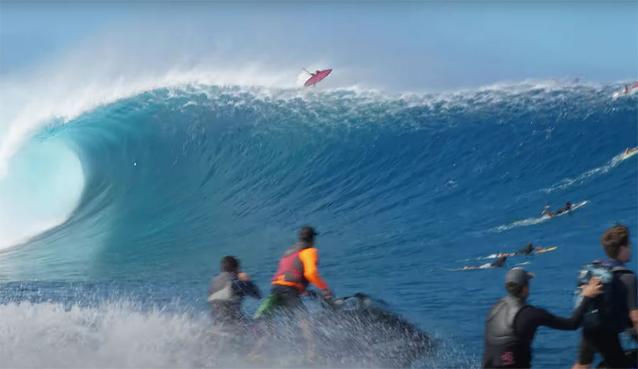 Surfers in Hawaii running from huge wave