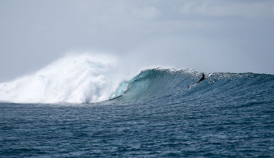Wave in the Maldives with surfer watching