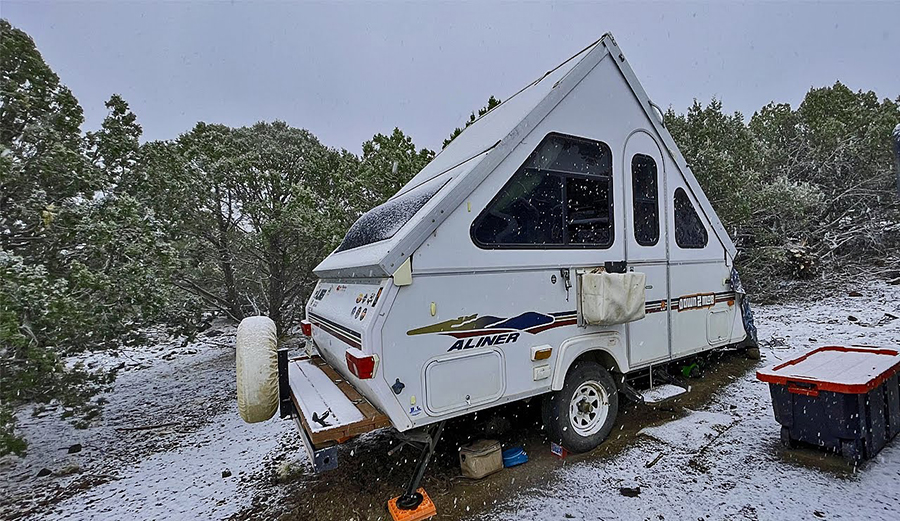An A-Frame camper parked during a snow storm.