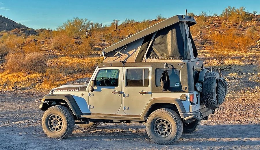 A 4x4 Jeep with a pop-top camper
