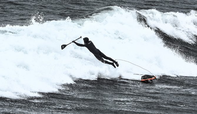 A Sup Surfer bails off a wave