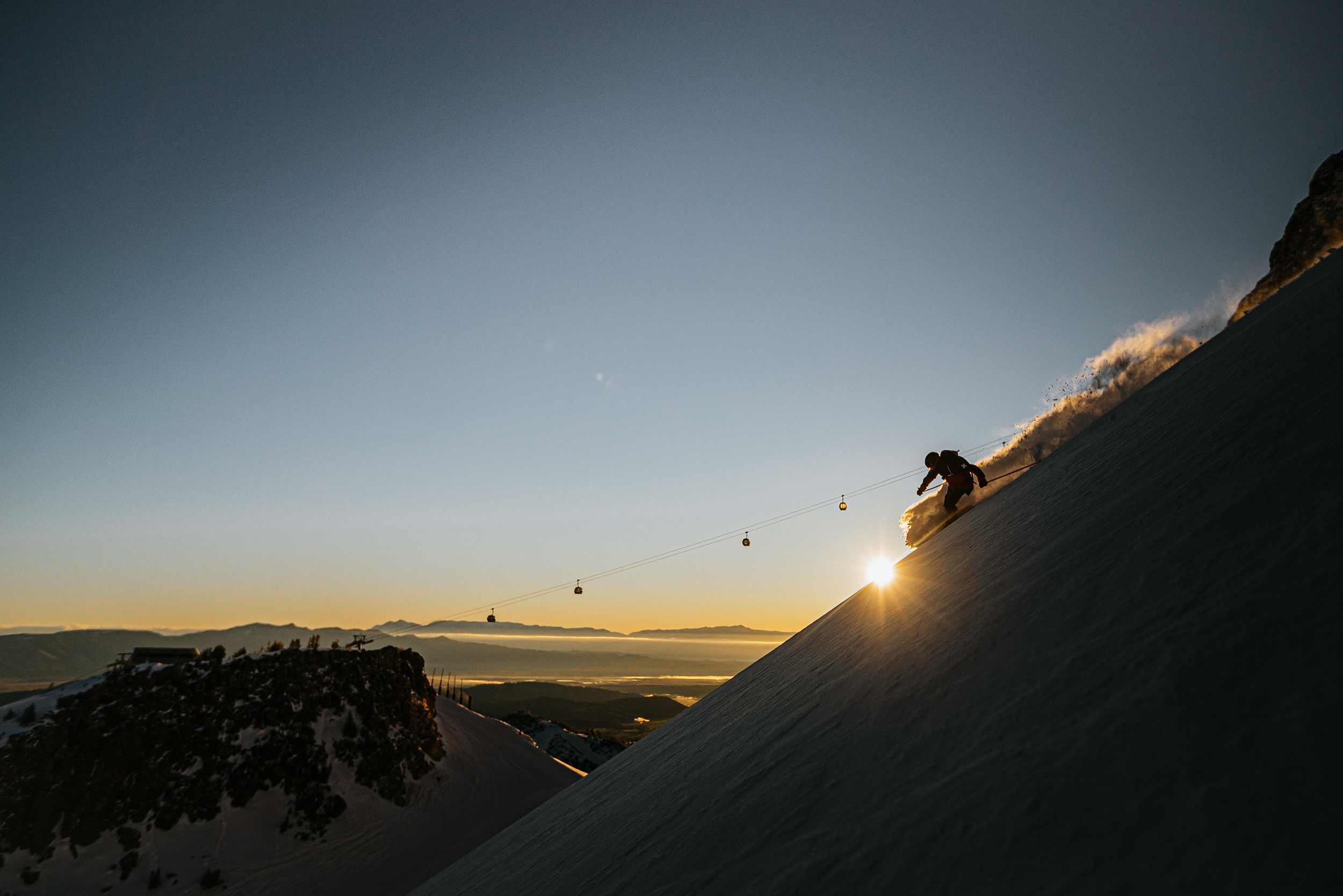 ski patroller skiing in front of the sunrise 