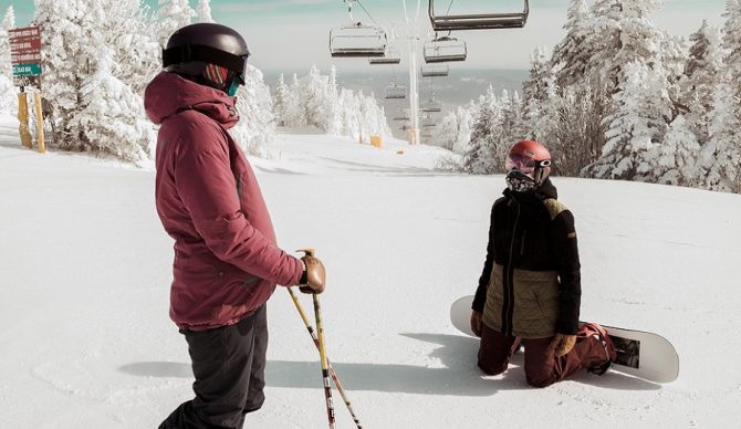 skier and snowboarder under the lift on a powder day