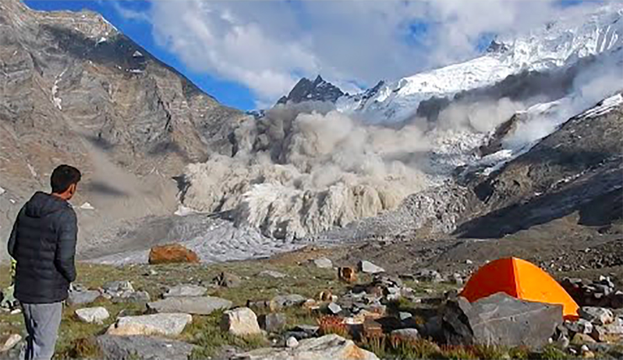 an avalanche rips down a valley in the Himalayas