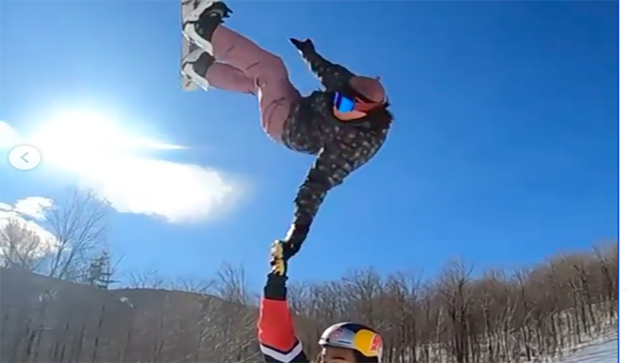 A snowboarder slaps a high five in mid air