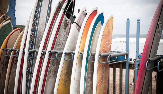 Composite surfboards sit in a rental rack
