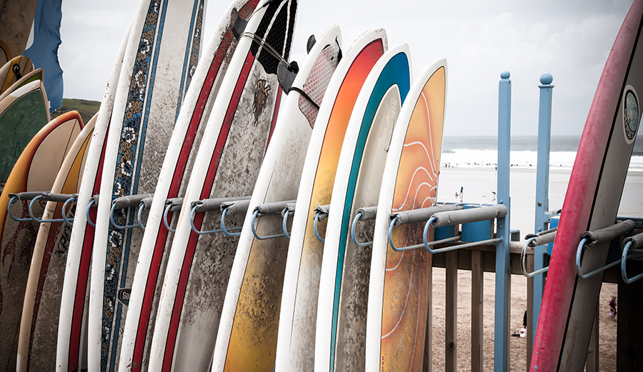 Composite surfboards sit in a rental rack