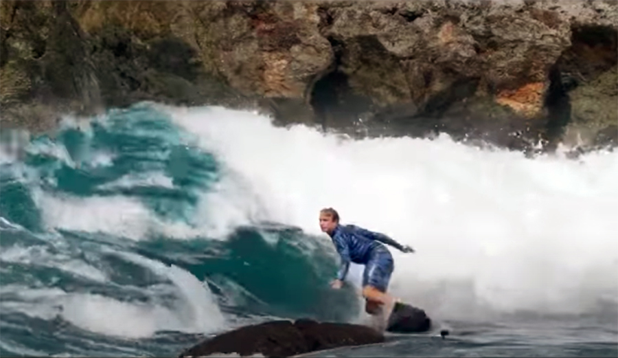 Jamie O'Brien surfs a wave at Shark's Cove right in front of a rock