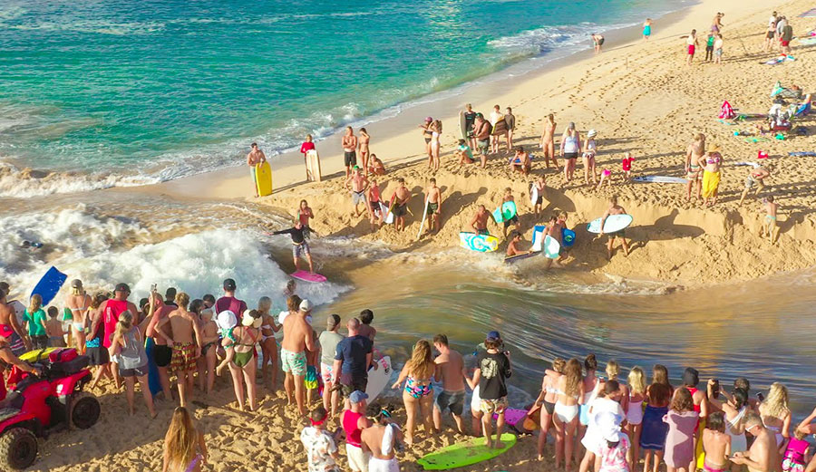 Crowd of people watching Waimea River surfers