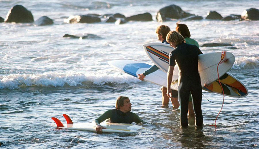 surfers with surfboards getting in the water