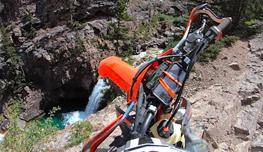 A dirtbike about to fall 100 feet into a waterfall pool