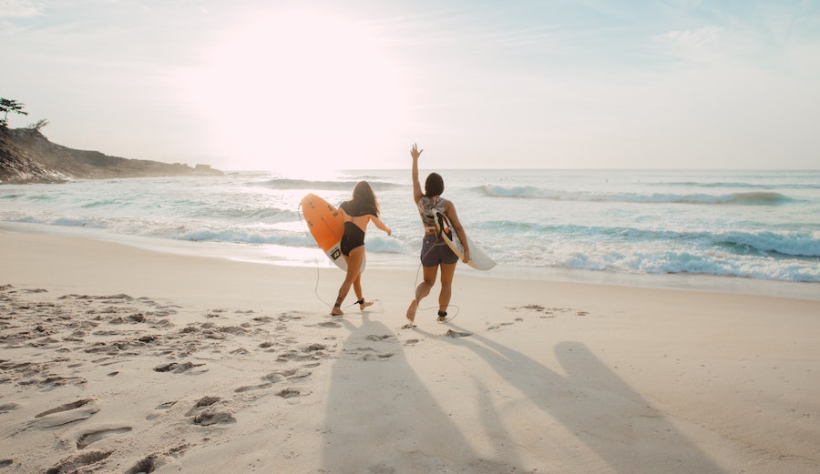 elizeu dias via unsplash two women surfers on the beach