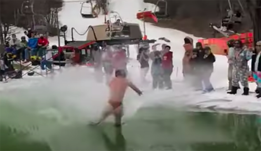 A snowboarder crashes during a pond skim