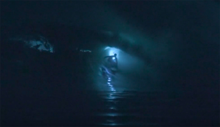 a surfer getting barreled at night