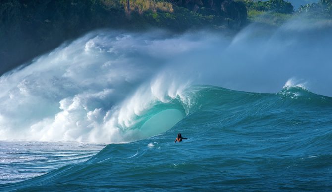 A surfer looks at a giant wave