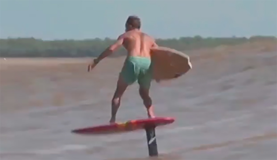 a foiler performs a board transfer on a tidal bore