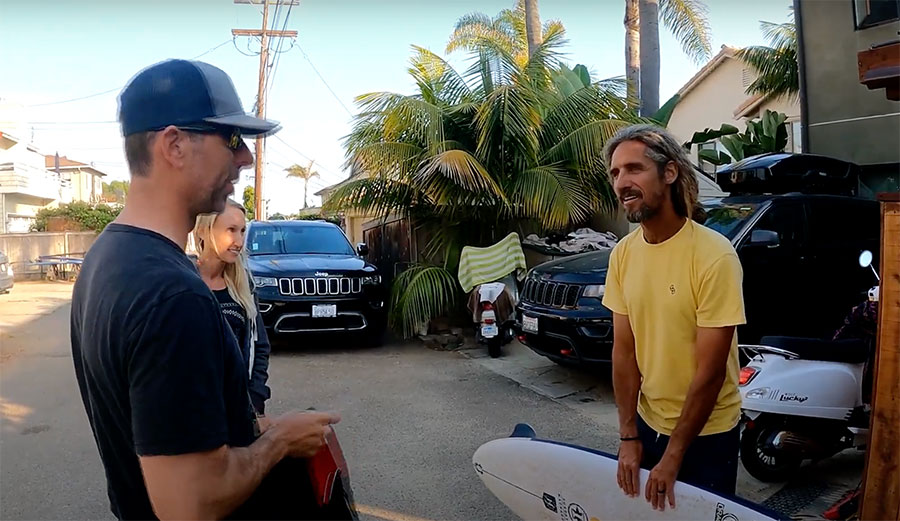 Rob Machado giving Pete Gustin a surfboard