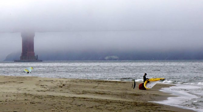 Fog covers the Golden Gate Bridge with two wingers in the foreground