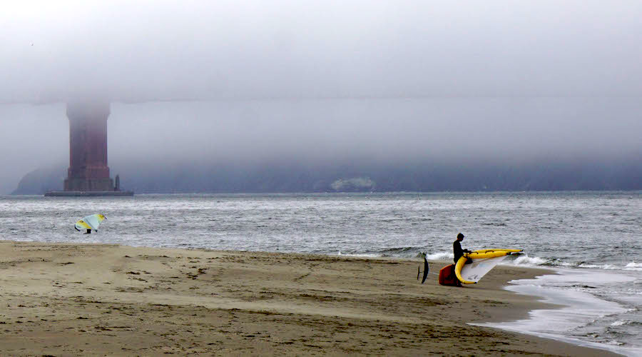 Fog covers the Golden Gate Bridge with two wingers in the foreground