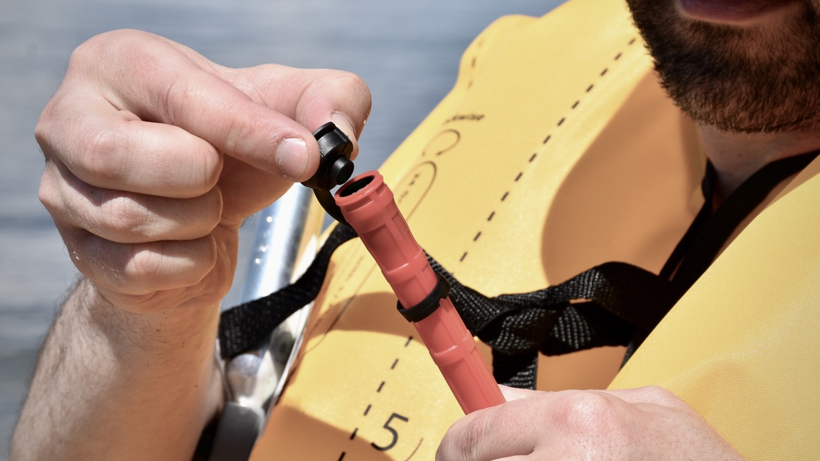 man deflating the NRS Zephyr inflatable life jacket