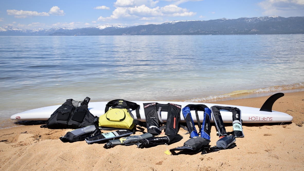 11 life jackets laying on a paddle board on the beach at lake tahoe