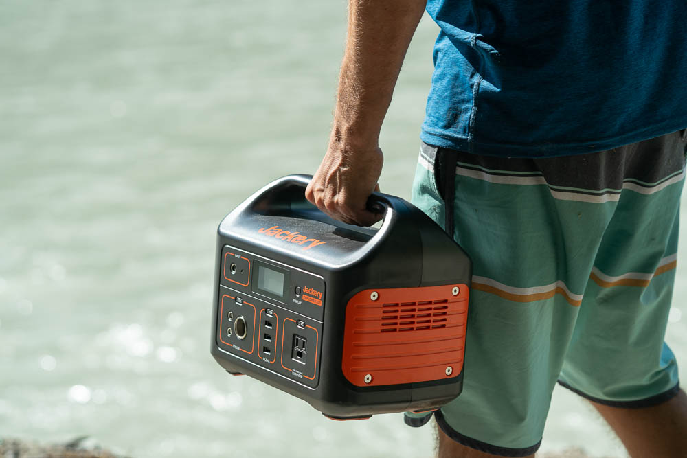 The Jackery Explorer 500 portable power station being carried next to a river.