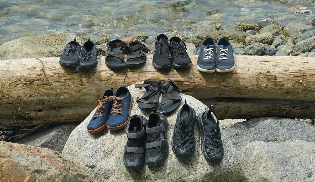 a group photo of the best water shoes we tested in 2024, sitting on a log and rock next to the water.