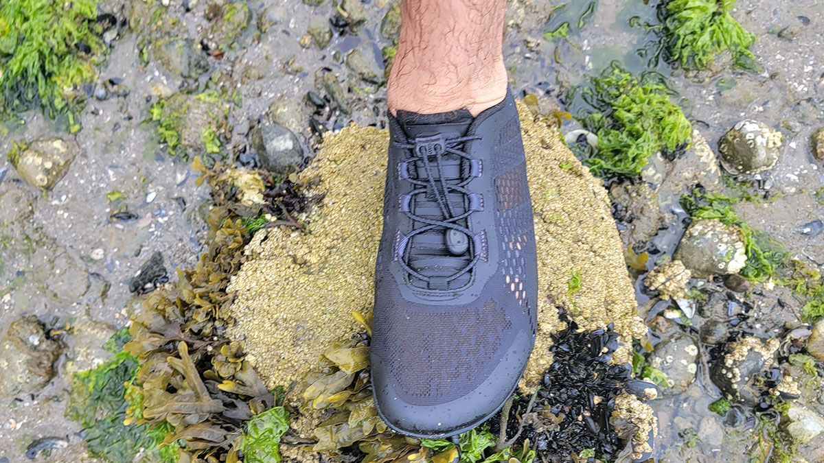Wearing the Xero Aqua X Sport water shoe on a rocky shoreline for our test of the best water shoes.