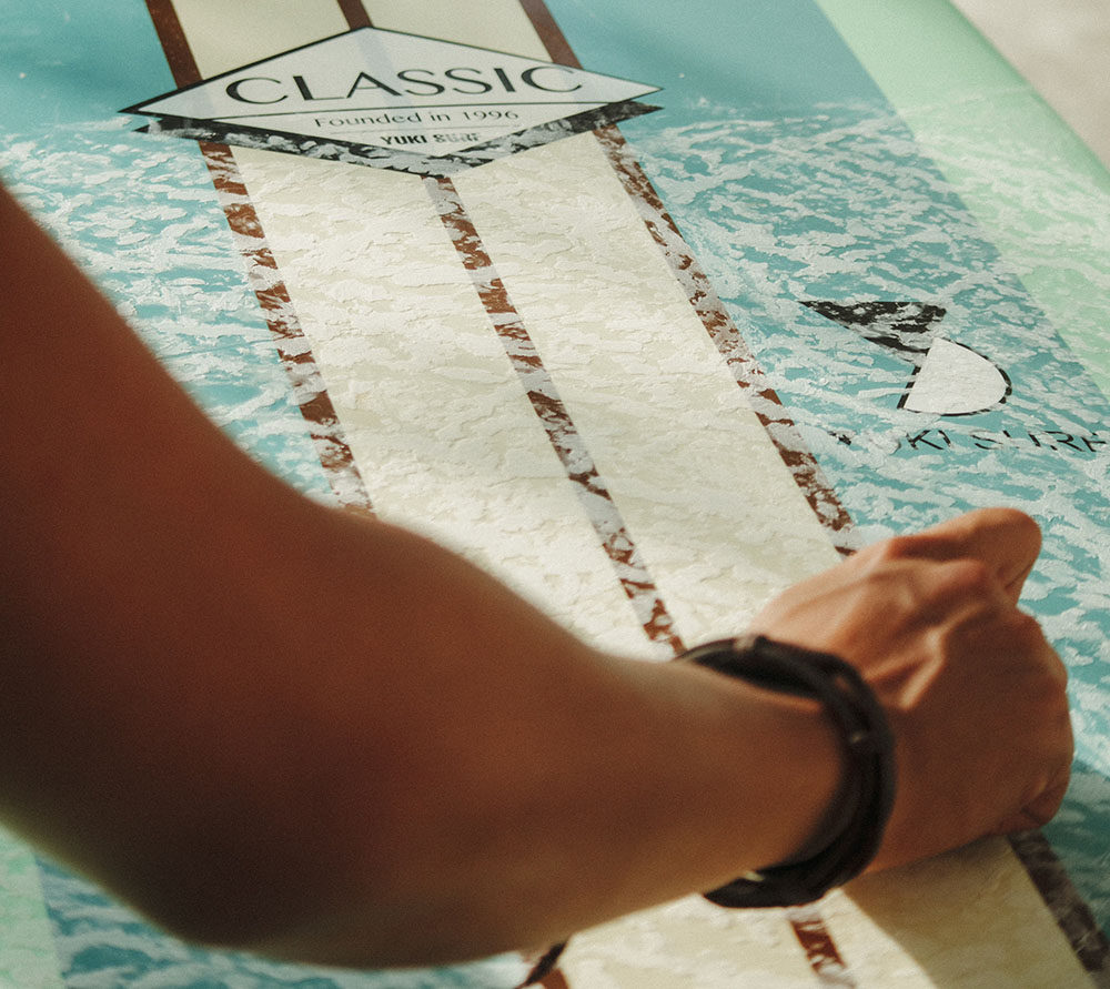 close up of an arm applying surf wax to a longboard