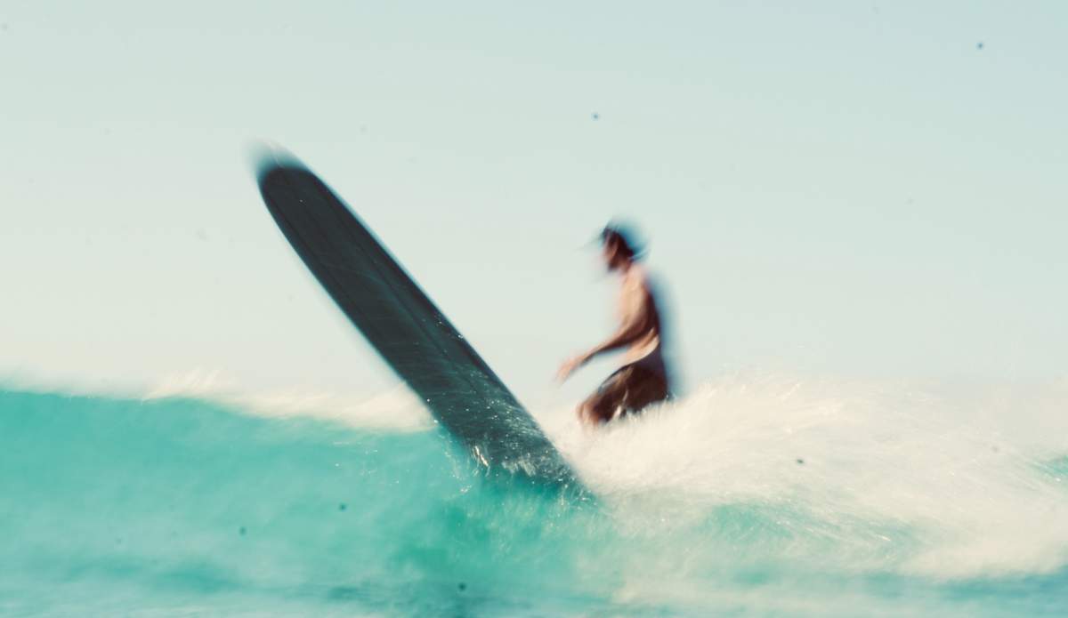 Longboard surfer finishes wave