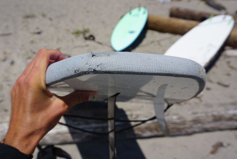 a close up of a soft top surfboard with dings on it, but still ok to ride