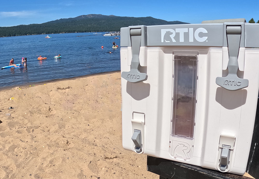 A view of the RTIC halftime water cooler next to a beach on a lake in the mountains.