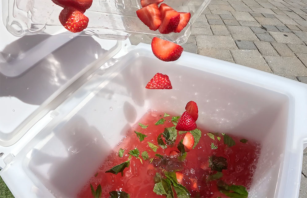 pouring out strawberries into the RTIC halftime water cooler to make a cocktail.